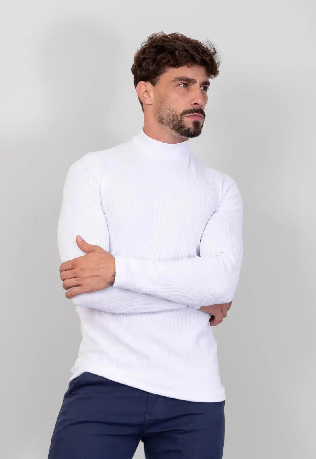 Modelo com camiseta gola alta canelada branca masculina CW Store de braços cruzados, destacando o caimento slim da malha com elastano